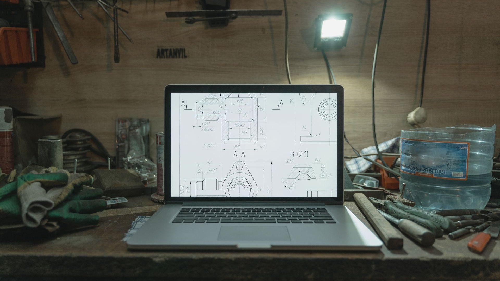 Laptop mit technischer Zeichnung auf einer Werkbank, umgeben von Werkzeug